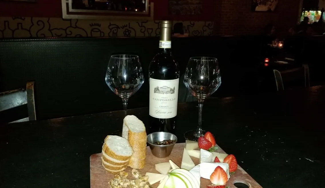 a table with a bottle of wine, glasses and food